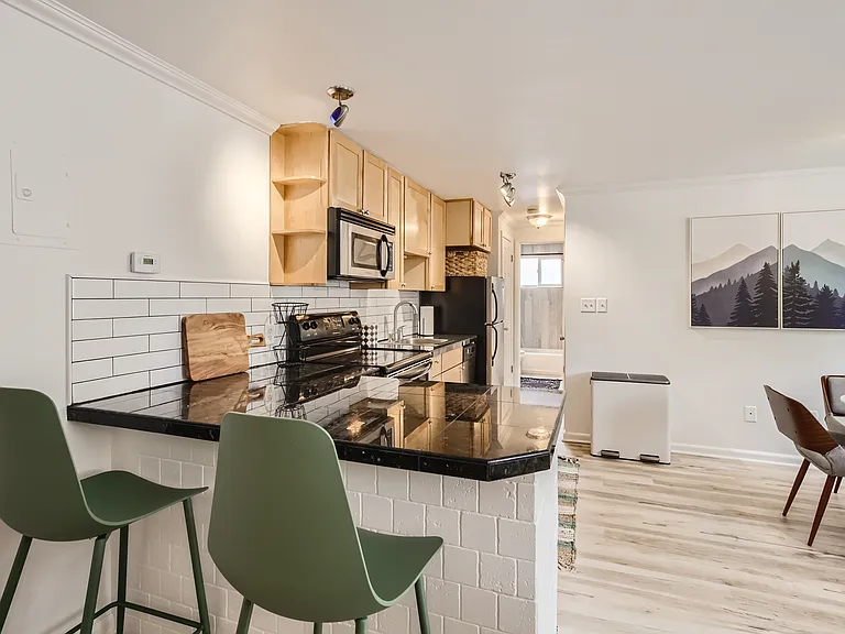 The kitchen features bar seating, granite countertops, modern subway tile backsplash, stainless steel appliances, & all the kitchen tools needed for your extended stay. Also included, is various cleaning supplies & a full-sized pantry for storage.