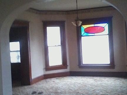 The first of three large living spaces features a distinctive stained glass window. The front door is located to the left in this picture. Three high archways connect the three carpeted living spaces. Your family's activities will define the space.