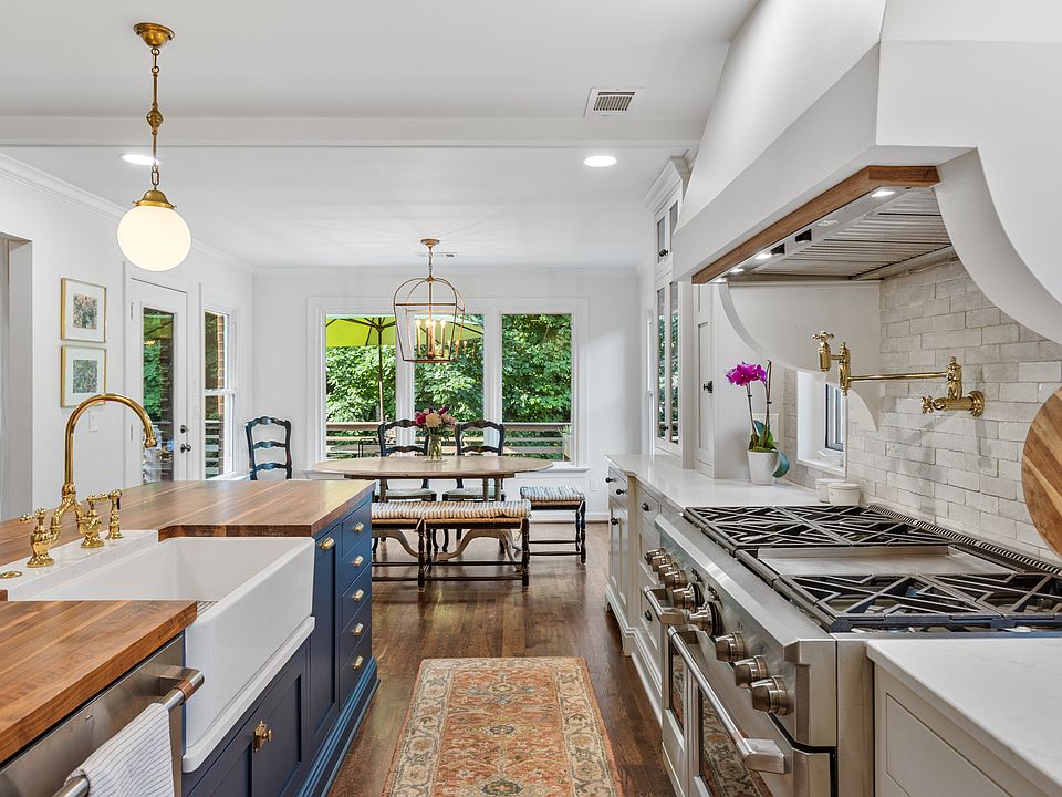 Recently updated state-of-the-art kitchen with a gas range, wall-mounted pot and kettle filler over the range, farm sink, and seating for four at the kitchen island.