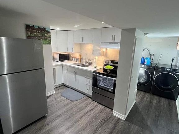 Cute and spacious White Kitchen Cabinets with Stainles Steele Refrigerator and Glass top Stove Appliances and Quartz Countertop. Laundry in a seperated area with modern washer and dryer with a Linen Closet for Extra Storage