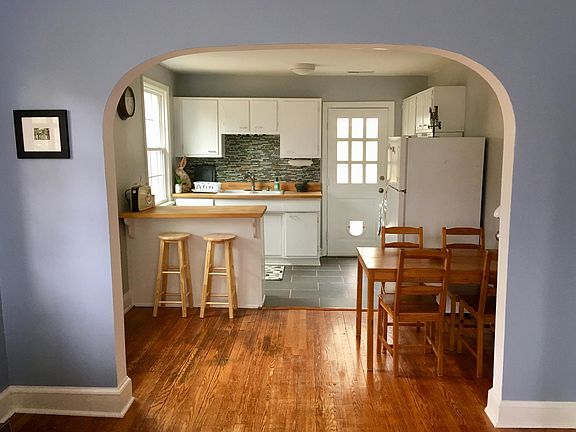 View from the living room to the dining area and kitchen, featuring original hardwood floors.