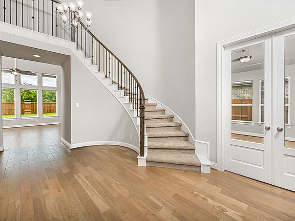 Dramatic curved staircase and French door entry to study in foyer
