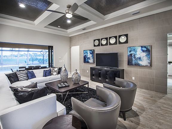 Model Representation; Gathering room with coffer ceiling and large sliding glass door leading to outdoor living spaces
