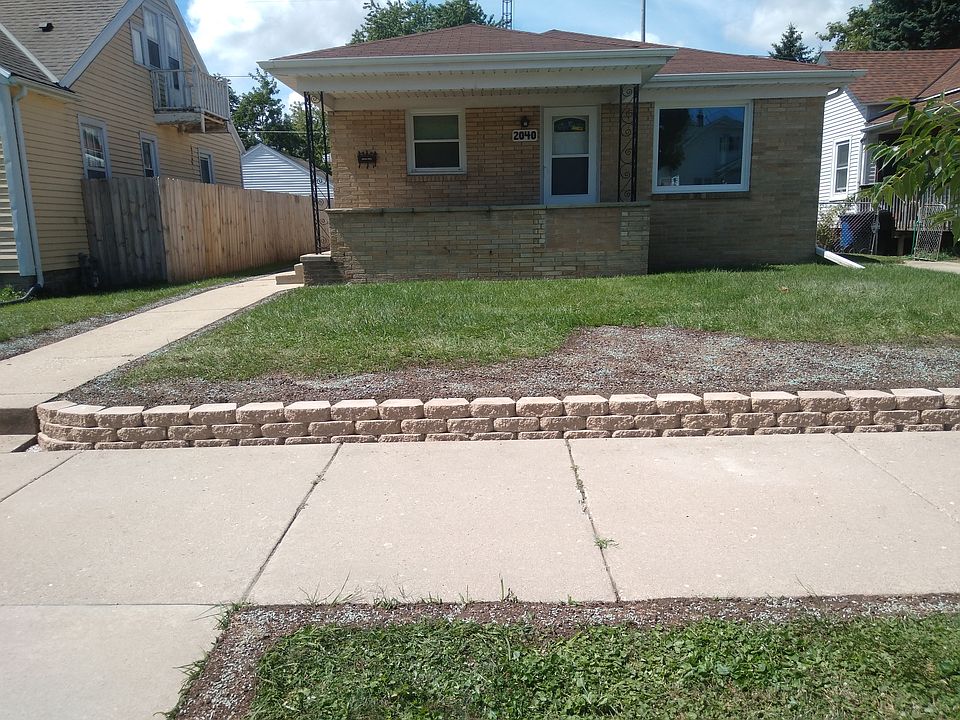 Front of home with new retaining wall, newer windows and doors, landscape grass re-planted.