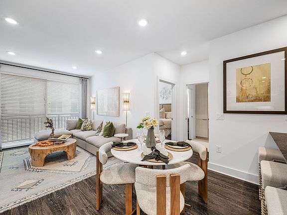 Modern open-concept living and dining area with cozy seating, elegant decor, and natural light streaming through large windows.