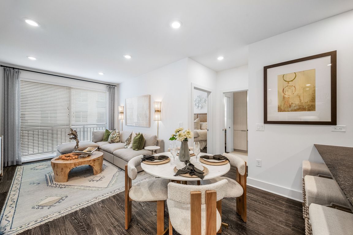 Modern open-concept living and dining area with cozy seating, elegant decor, and natural light streaming through large windows.