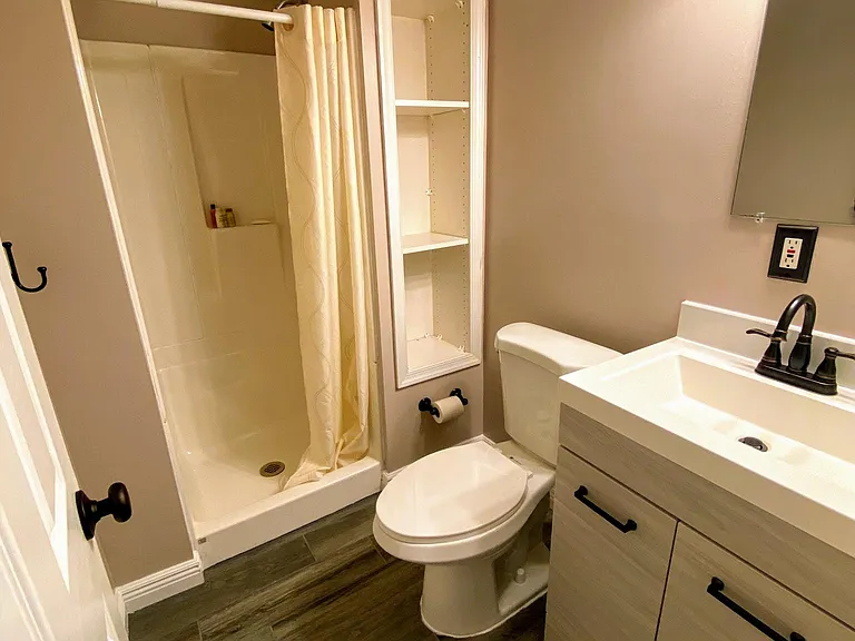 Full bathroom in the basement with tile floors, integrated storage shelves, and all new vanity.