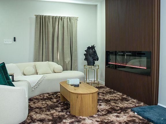 Enjoy a chic living area with a curved boucle sofa, modern fireplace, and elegant wood-slat accents.