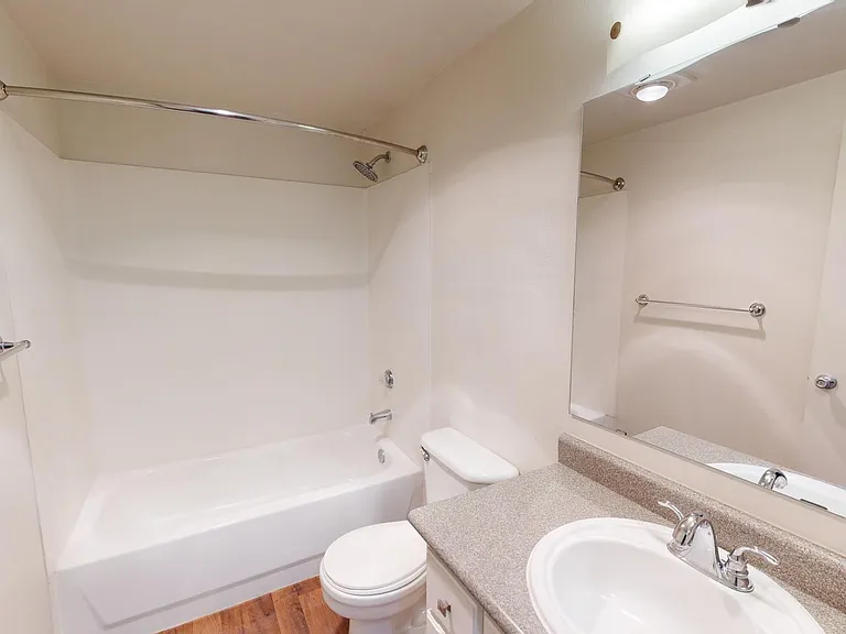 Apartment bathroom with wood-style flooring.