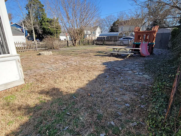 Fenced back yard with shed, fire pit, and playset