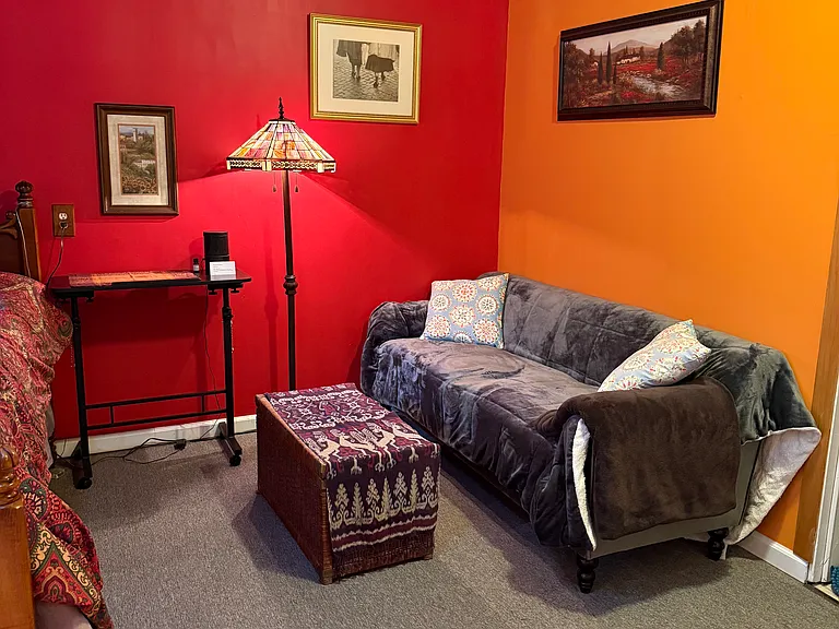 Adjustable standing or sitting desk and comfy couch. Reflection on ceiling is from the stained glass light.