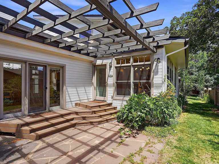 A thoughtfully designed pergola adds both beauty and shade to this private outdoor gathering space, extending the home's living area into the outdoors.