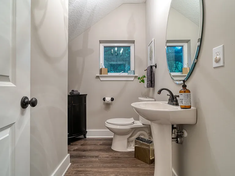 Conveniently located right off the main communal areas, this pristine powder room features a classic pedestal sink and bright, welcoming design