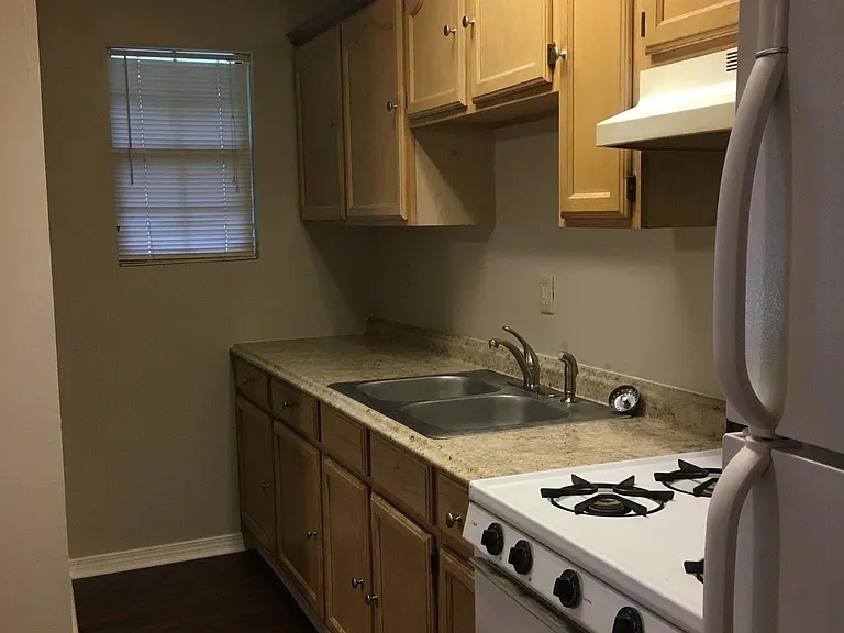 Kitchen with lots of cabinets, gas stove and refrigerator