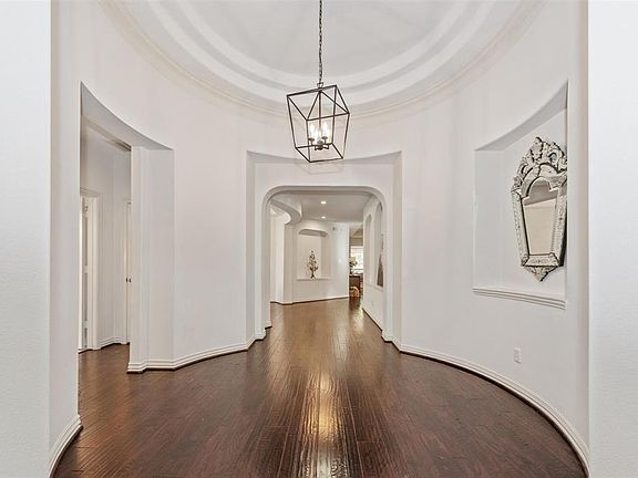 This home welcomes you with an absolutely stunning hallway complete with coffered ceiling, wood flooring, art niches, and crisp and clean walls with crown molding.