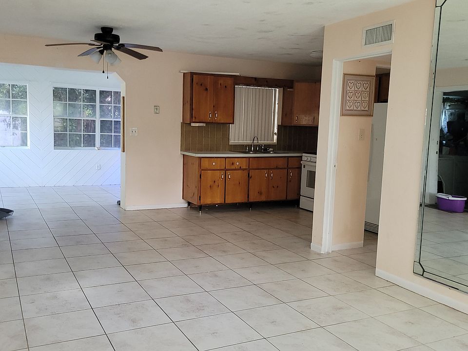 Looking into living room, sunroom and kitchen area from front door.. Mirrored wall..