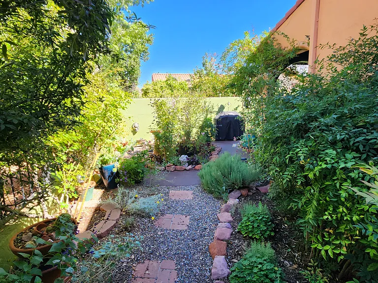 The backyard is a delightful, walled garden full of flowering plants, and provides both a covered sitting area and lovely strolling path.