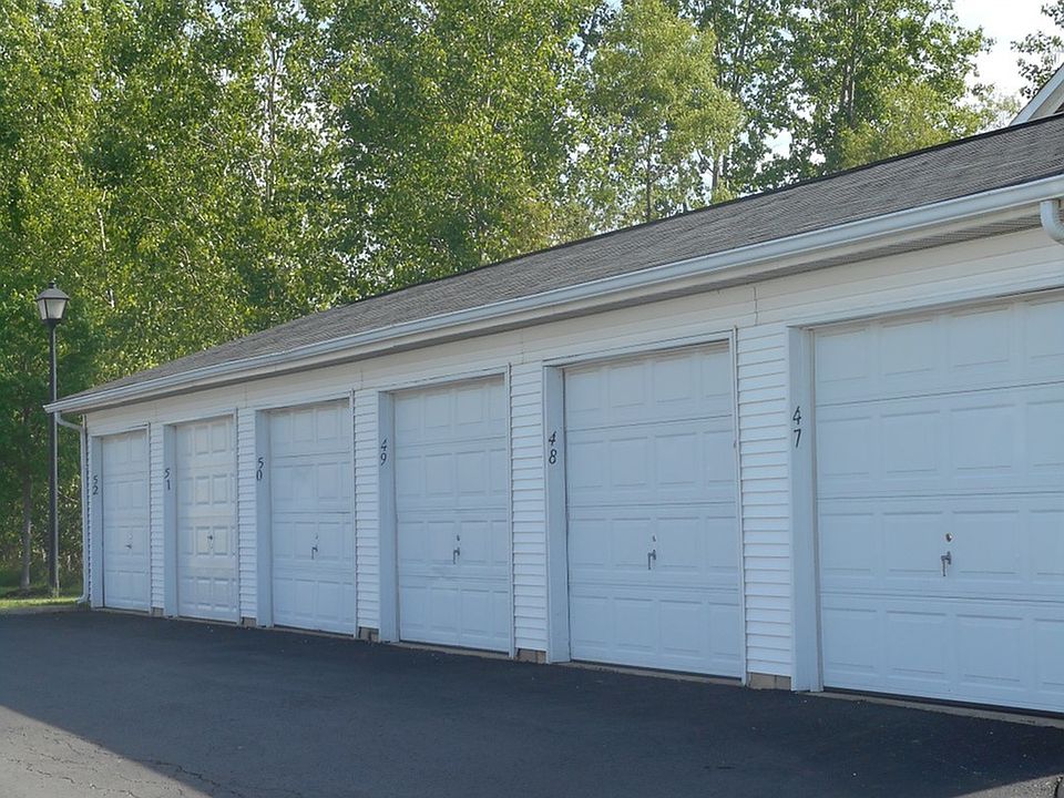 Templeton Crossing Exterior: Row of connected white one car garages; tall black lamp post and luscious trees.