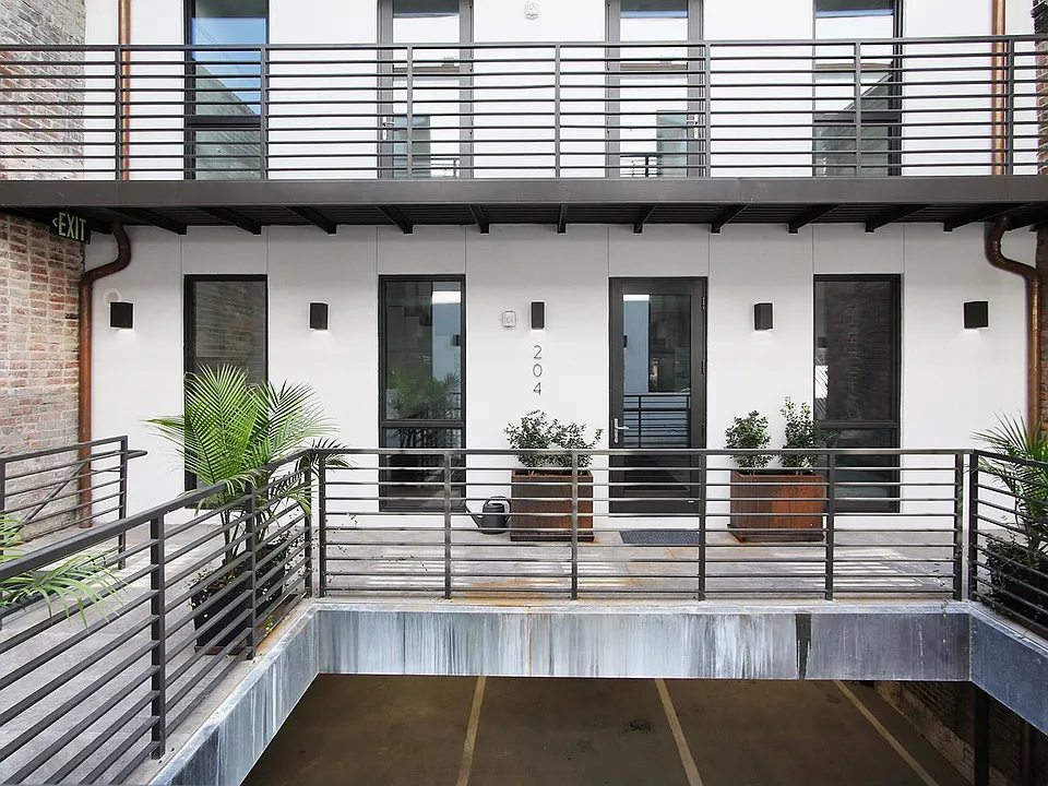 Front view of Unit 204 from the shared courtyard (parking garage below).