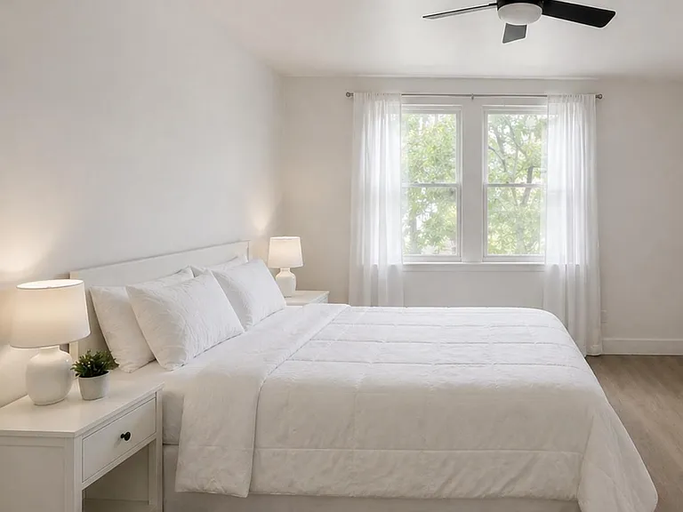 Spacious bedroom with a large window, ceiling fan, and room for a full or queen bed plus nightstands.