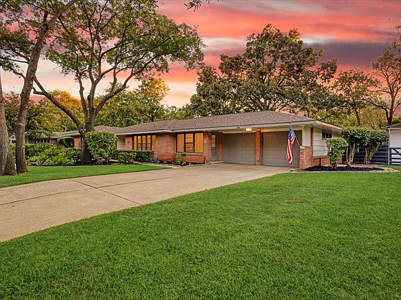 Front of House featuring a fully landscaped front lawn, brick siding, concrete driveway, and 2 garage doors
