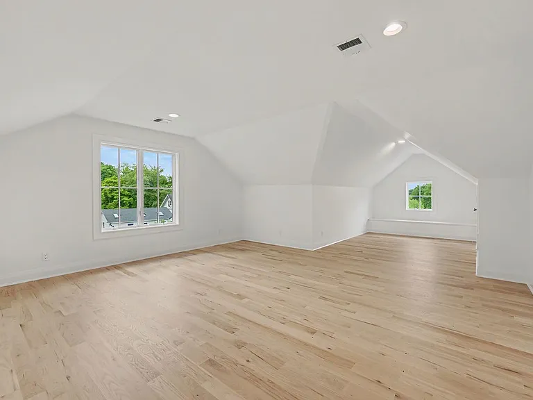 The third level bonus suite serves as a flexible living area, thoughtfully arranged to support both a comfortable bedroom and a private office workspace.