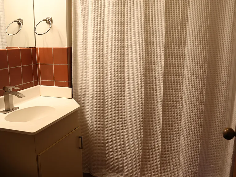 A clean and functional bathroom features classic tilework, a full tub-shower combo, and modern lighting.