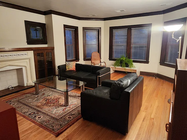 Living Room includes a leather couch and armchair, antique rocking chair, glass coffee table, Oriental rug, two plant stands, credenza, cabinet and large screen TV.