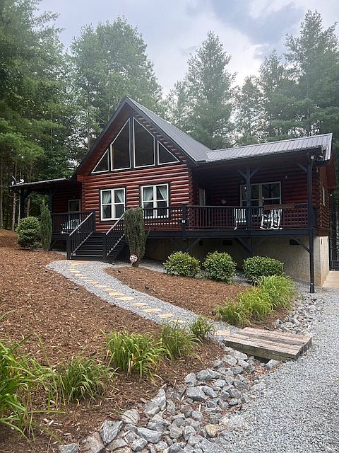 Newly painted inside and out cabin has a long gravel driveway and a cement area with a basketball hoop. Those are all lilies that bloom bordering the driveway.