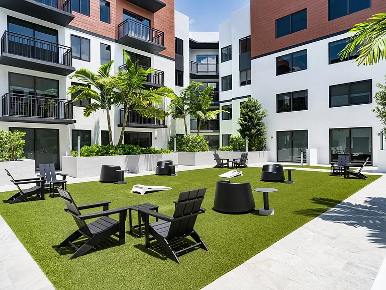 Central courtyard with Adirondack seating, outdoor games, and palm-framed gathering areas designed for neighborly connection.
