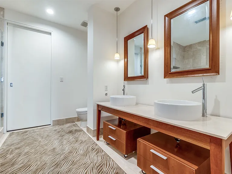 Full bathroom featuring double vanity and a shower stall