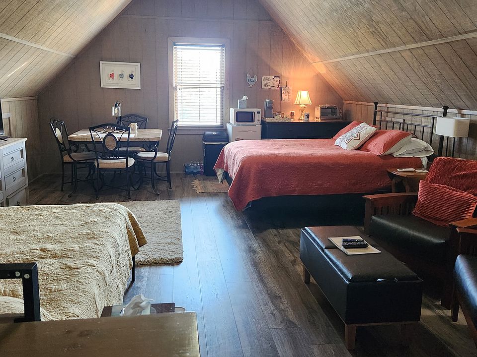 Overview of studio with 2 sleeping areas (2 queen beds), large dining/work space table, sitting area, kitchenette