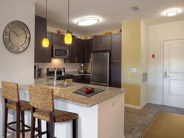 Classic Package kitchen with espresso cabinetry, beige speckled granite countertops, white tile backsplash, stainless steel appliances, and hard surface flooring