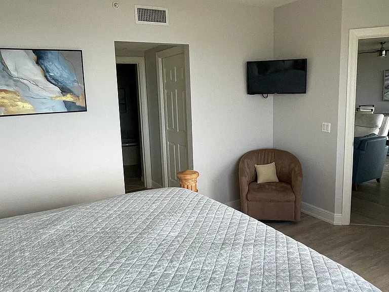 TV, chair, and 2 walk-in closets complement this master bedroom