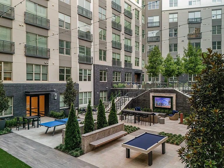 Modern apartment courtyard featuring lush greenery, outdoor seating, and recreational areas with a sleek urban design.
