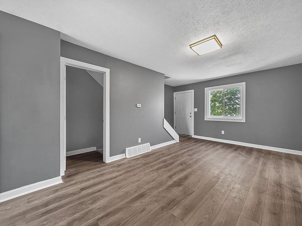Living room with luxury vinyl plank flooring. Facing the front door entrance, door leading to basement stairs, as well as stairs leading to the upstairs bedrooms.