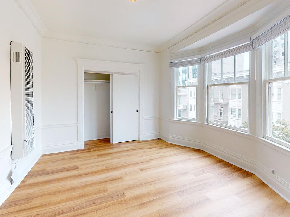 Spacious room with a wood-like flooring, large window, and a closet