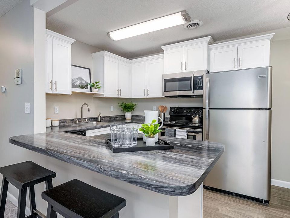 Modern kitchens with black fusion countertops, wood-style flooring, and a breakfast bar.