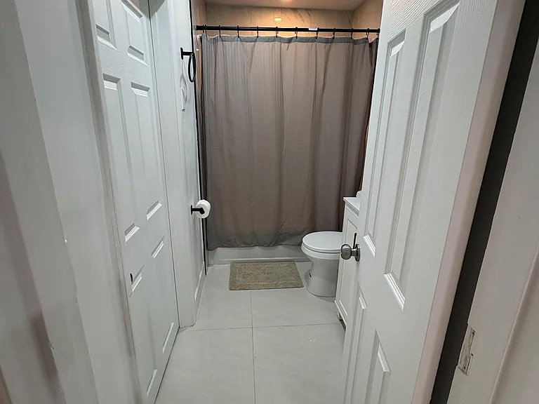 Full bathroom with tiled floors, a shower/tub with curtain, and a compact vanity for everyday convenience.