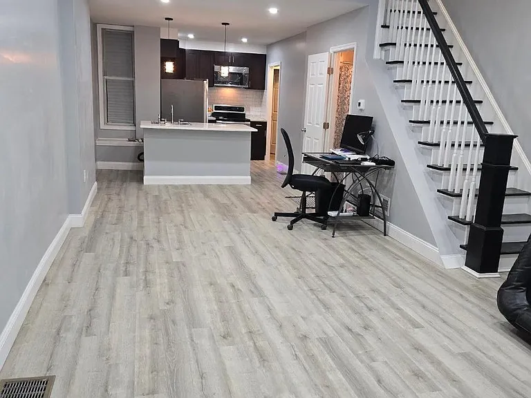 Open-concept living area with durable flooring, recessed lighting, and a breakfast bar connecting to the kitchen.