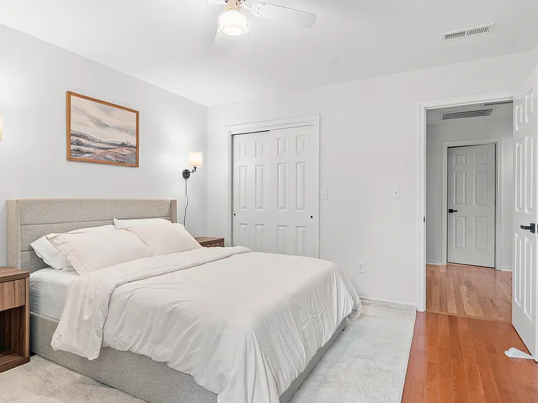 Comfortable upper-level bedroom with a queen bed, dresser, ceiling fan, and closet storage.