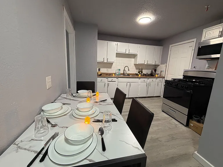 Eat-in kitchen with a dining table, ample white cabinetry, subway-tile backsplash, and a full appliance package.