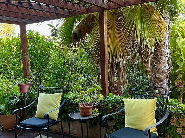 Peaceful shaded deck furnished with cushioned wrought-iron chairs and a side table.