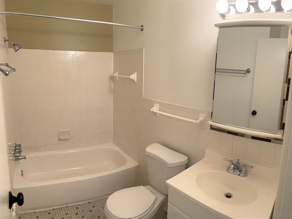The bathroom is a full bath with tile flooring. There is ample shelving storage directly across from the vanity.