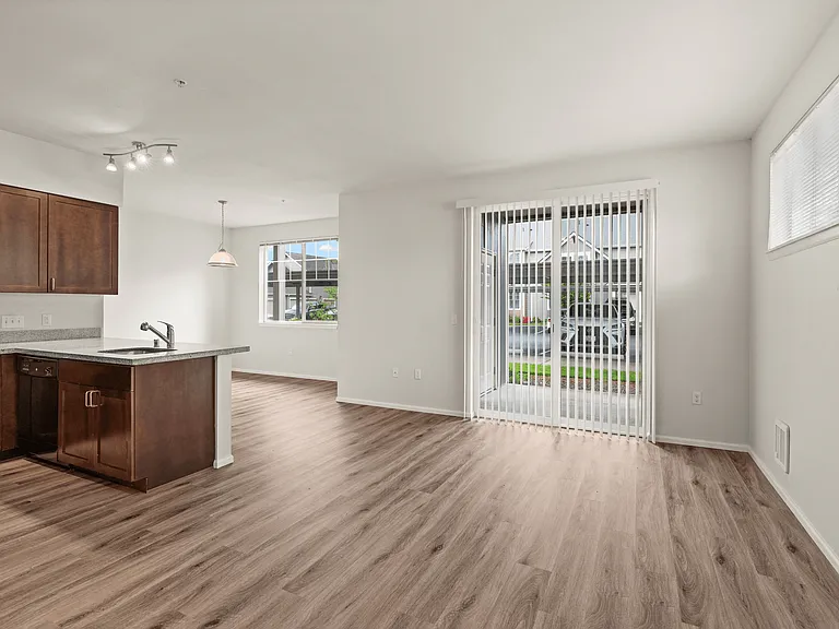 Bright open-concept living area with sliding glass door and kitchen breakfast bar at Port Landing at Fife in Fife, WA. Bright open-concept living area with sliding glass door and kitchen breakfast bar at Port Landing at Fife in Fife, WA.