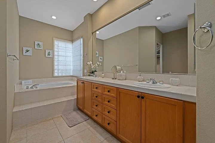 En suite bathroom for primary bedroom. Full tile shower, sunken tub and dual vanity sinks as well as large walk in closet.