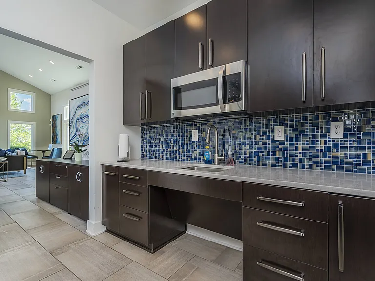 Step into a stylish kitchen featuring dark brown cabinetry and a vibrant blue tile backsplash, designed for both cooking and entertaining.