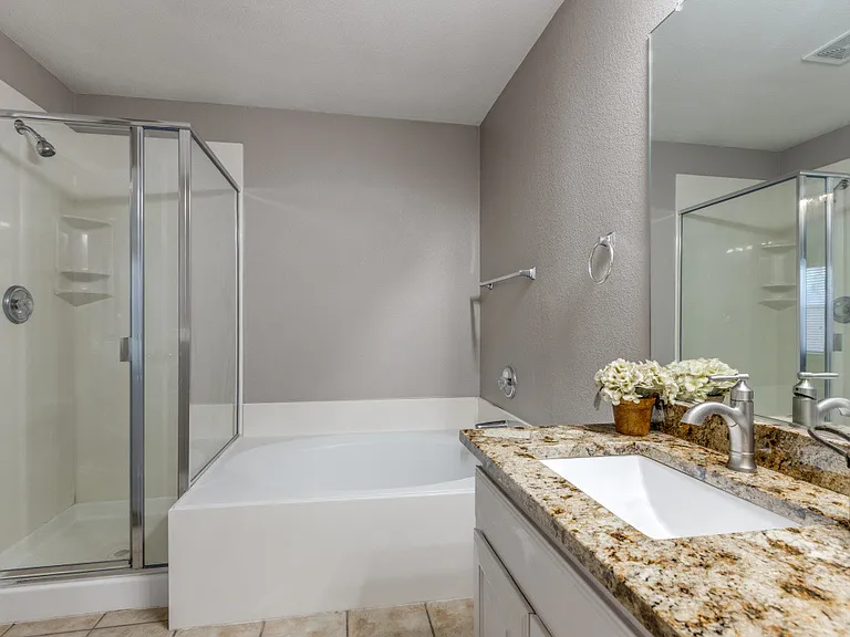 Primary bath with granite counter tops, updated lighting, 2 sinks, stand up shower and garden tub.