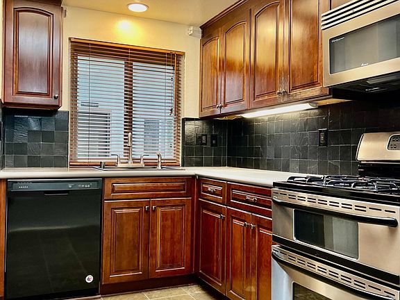 Black tile backsplash, updated counters and cute kitchen window make you want to cook in this cozy kitchen