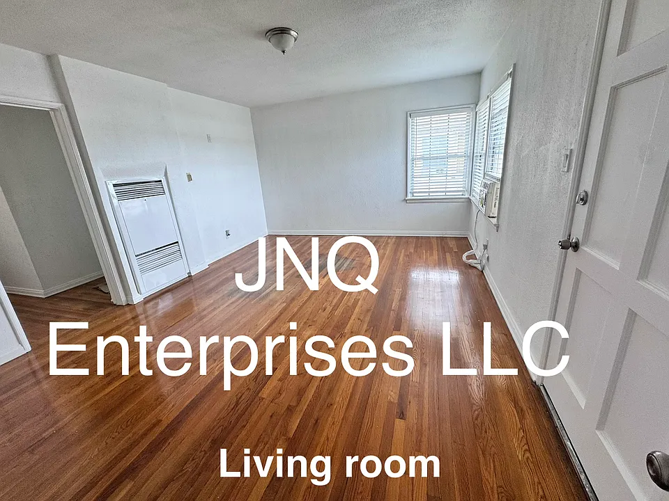 Freshly painted comfortable size living room with new air conditioner and refinished hardwood floors .